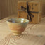 Ceramic cup on a wooden surface with a gift box in the background