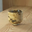 Ceramic cup with black speckles on a wooden surface