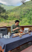 Person preparing tea outdoors with a scenic background